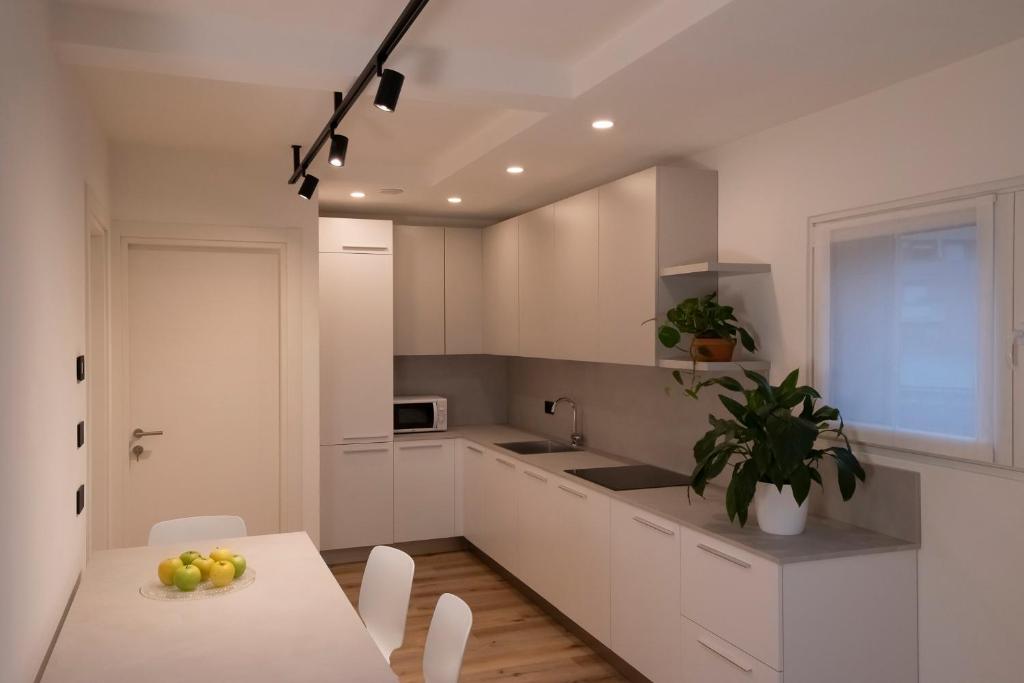 特伦托SILVANELLO Apartment的厨房配有白色橱柜和水果桌