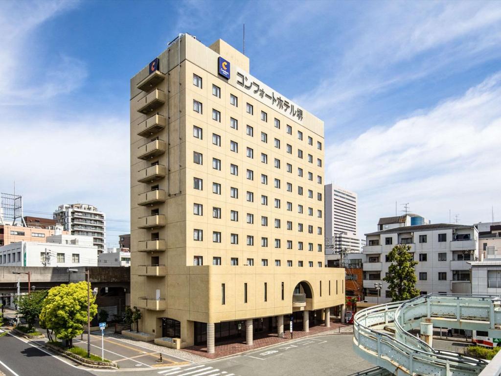 堺市舒适酒井酒店 的一座高大的白色建筑,上面有标志