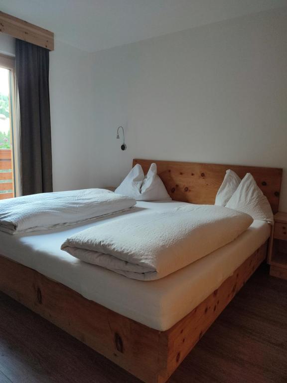 巴迪亚Apartments B&B Pretermo的一间卧室配有一张带白色床单的木床