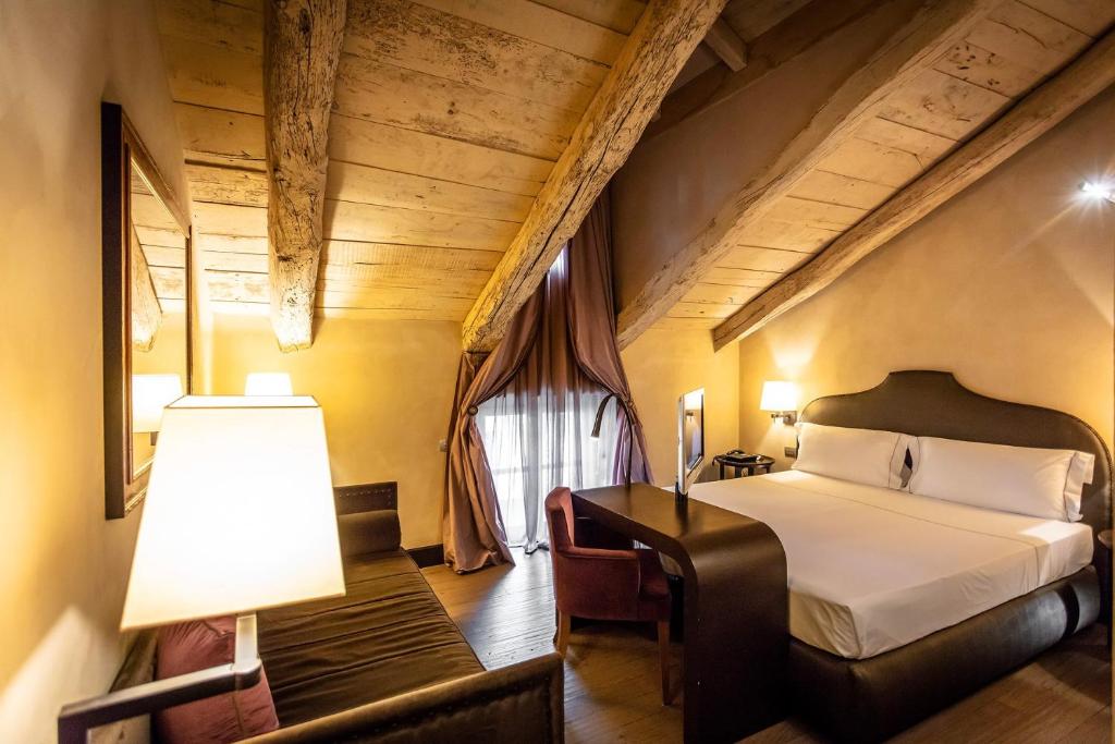 福萨诺帕拉佐莱希尼酒店的一间卧室配有一张床和一张带台灯的书桌