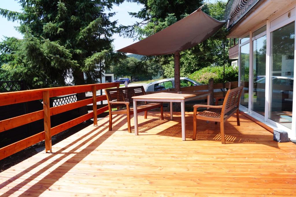 温特贝格WinterbergerQuartier的木制甲板配有桌椅和遮阳伞