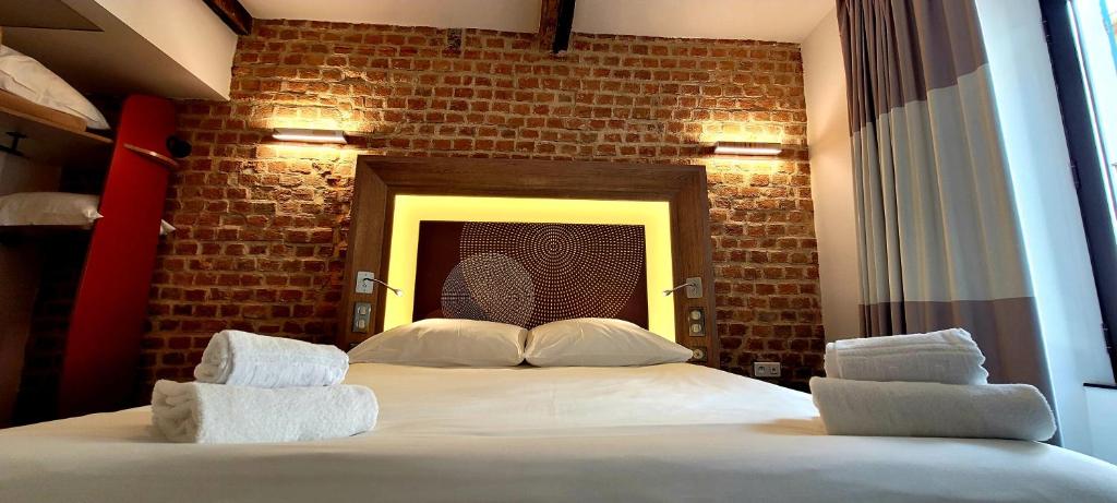 阿雅克修Kallisté的一间卧室设有一张带砖墙的大床