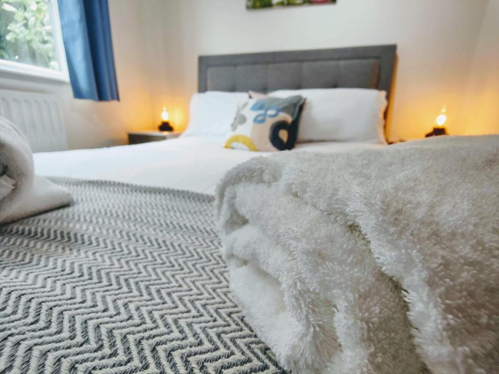 伊斯特雷格CEDAR HOUSE - Spacious 4Bedroom House 2Bath Kitchen SmartTV Lounge Garden Wifi FreeParking的一间卧室配有一张带白色毯子的床
