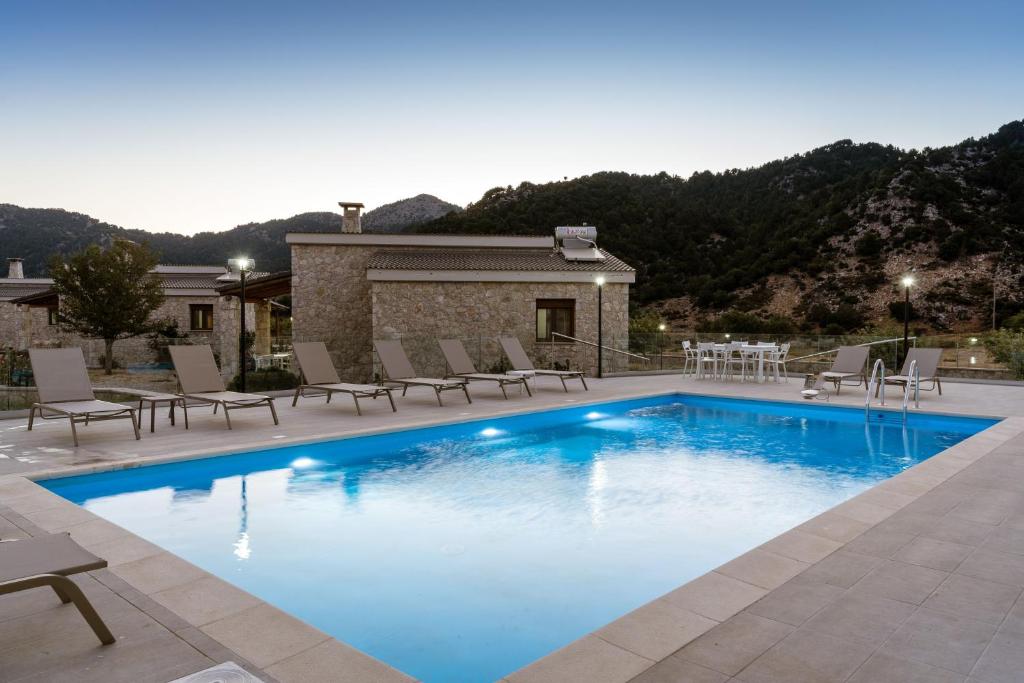 奥马洛斯奥马洛斯村别墅的一个带椅子的游泳池以及一座房子