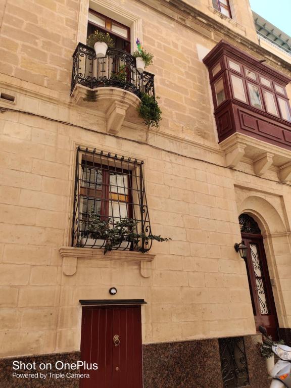 森格莱阿Semi-basement, cosy apartment interconnected to our residence a traditional Maltese townhouse的一座带2扇窗户和阳台的建筑