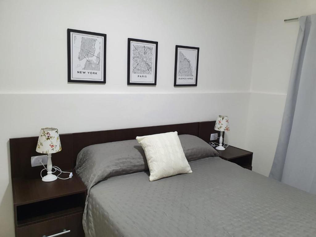 卡塔马卡Apart Ocampo Catamarca II的卧室配有一张墙上三幅照片的床