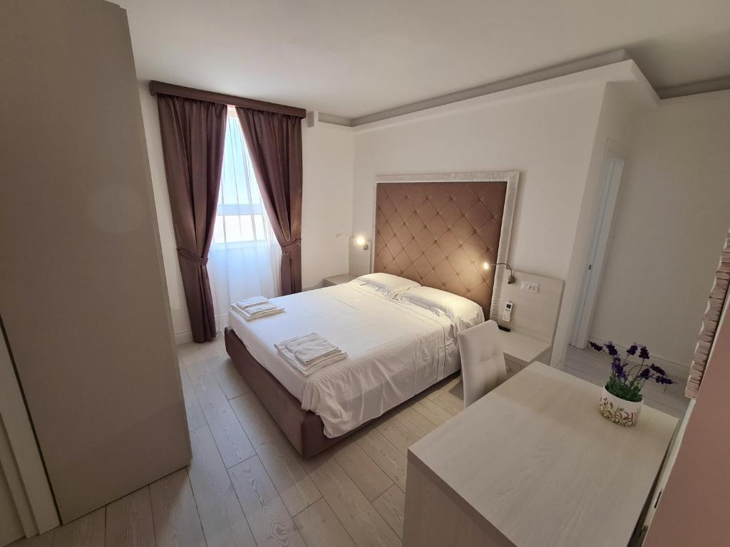 马达莱纳L'Isola nel Parco Boutique Rooms & Apartments的卧室配有一张白色的大床和一张桌子