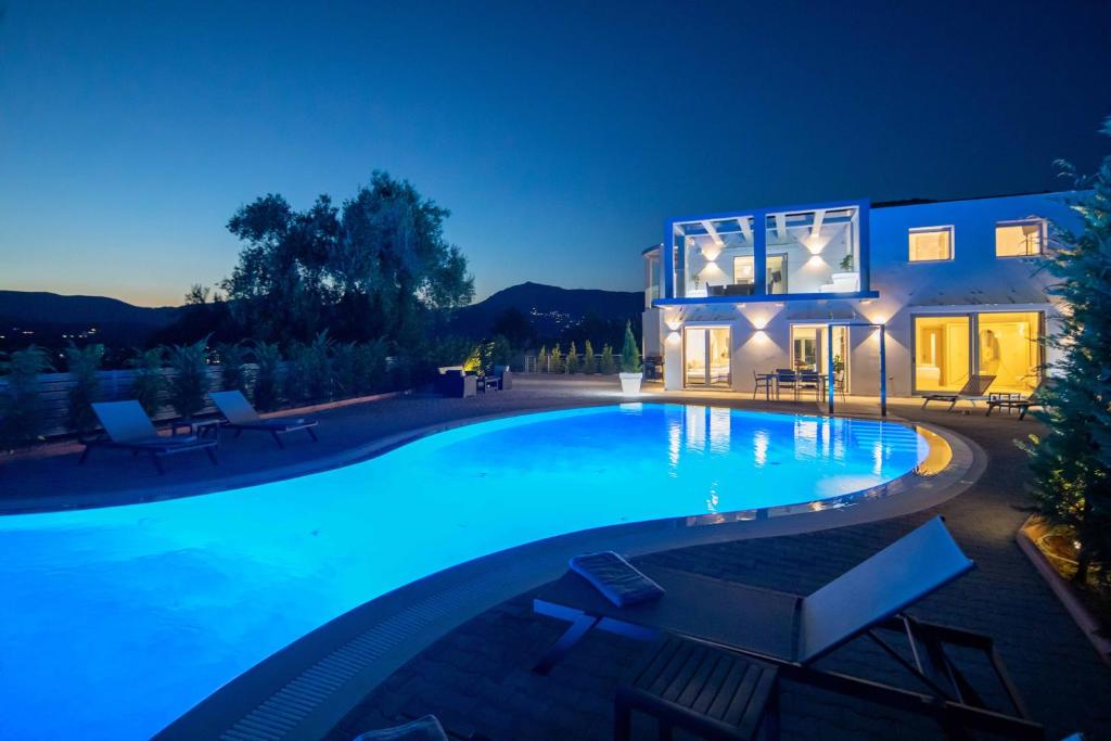 科梅诺Five Stars Villa的夜间在房子前面的游泳池