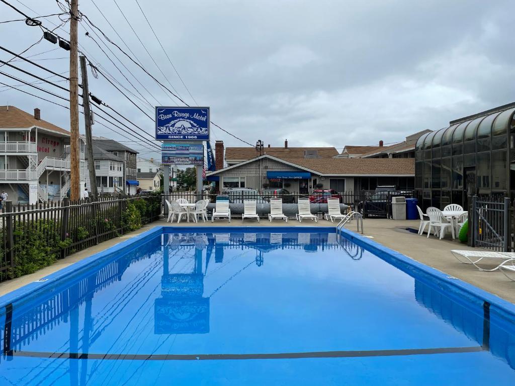 旧奥查德比奇Beau Rivage Motel的一个带桌椅的大型蓝色游泳池