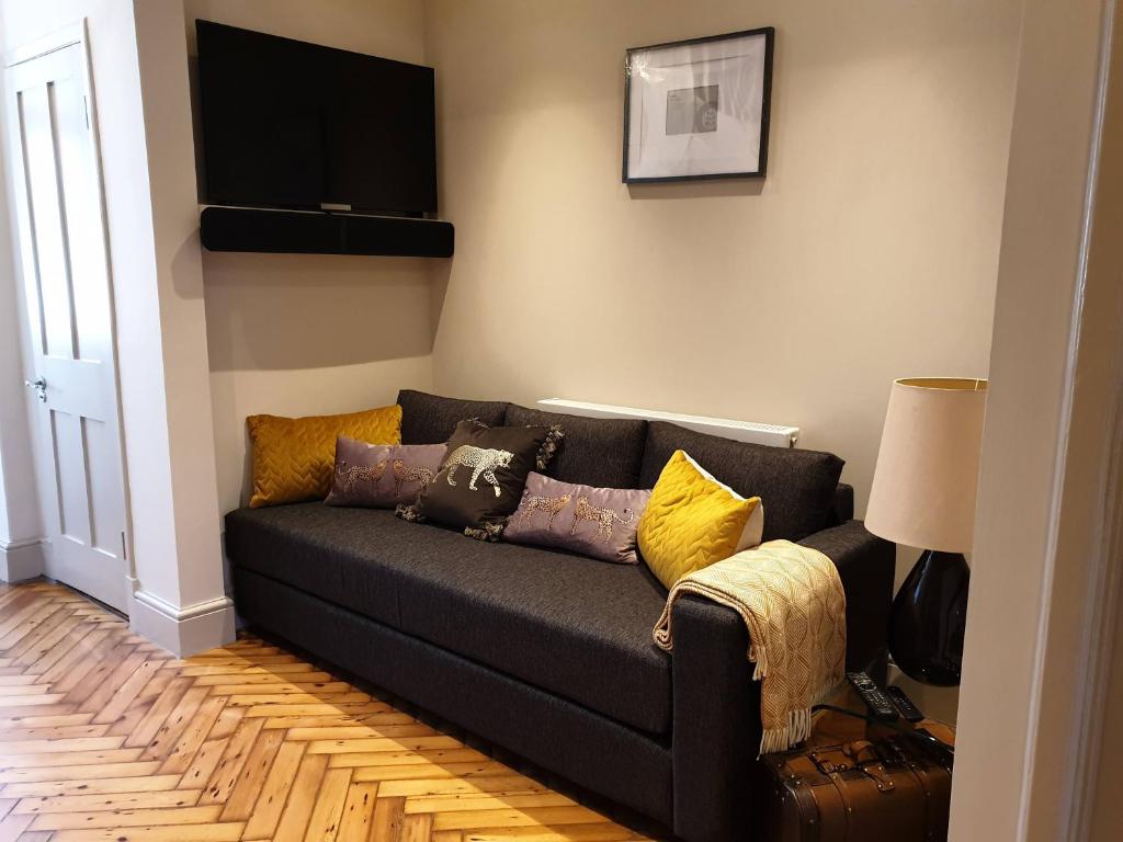 伦敦St Paul's Studios apartment的客厅配有带枕头的黑色沙发