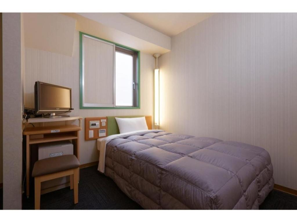 神户R&B Hotel Kobe Motomachi - Vacation STAY 40714v的一间卧室配有一张床和一张书桌及电视