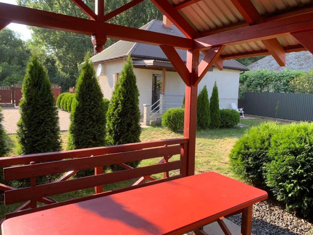 ShomPrivate House near Kosyno的坐在院子凉棚下的红色长凳