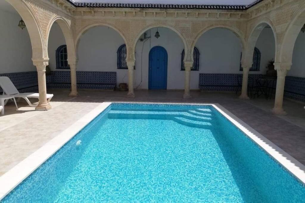 乌姆苏克Maison typiques (houche) avec piscine的大楼内的一个蓝色海水游泳池