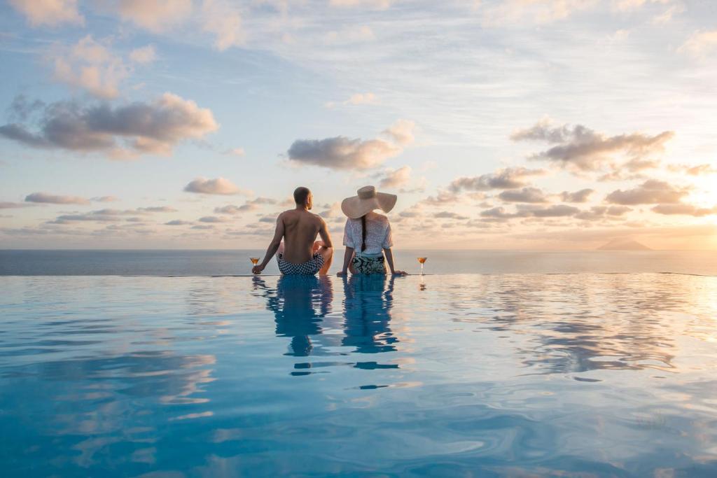 马尔法瑞维斯酒店的两个男人坐在度假村的无边泳池里