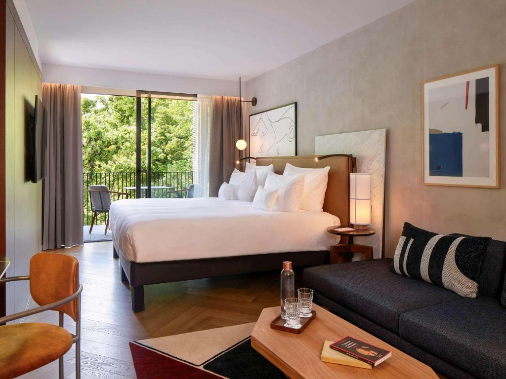 科尔马L'Esquisse Hotel & Spa Colmar - Mgallery的酒店客房设有一张大床和一张沙发。