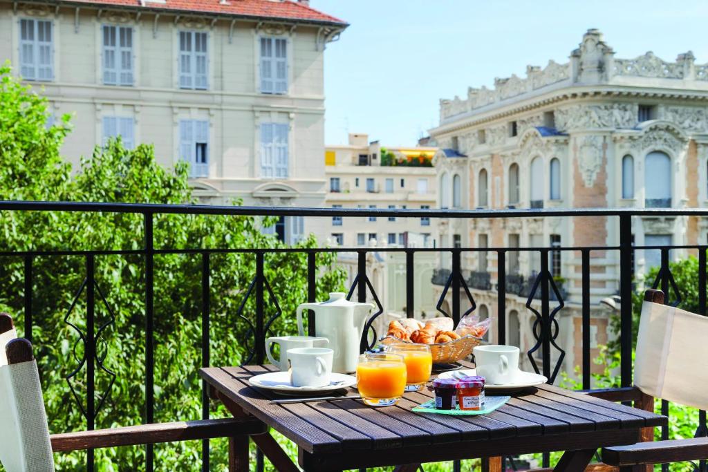 尼斯La Malmaison Nice Boutique Hôtel的阳台上的桌子上摆放着食物和橙汁