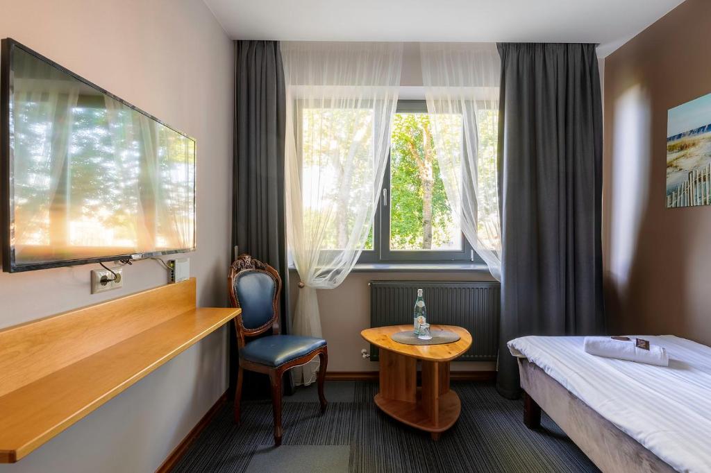 库尔迪加Comfort Hotel Kuldiga的酒店客房设有床、桌子和窗户。