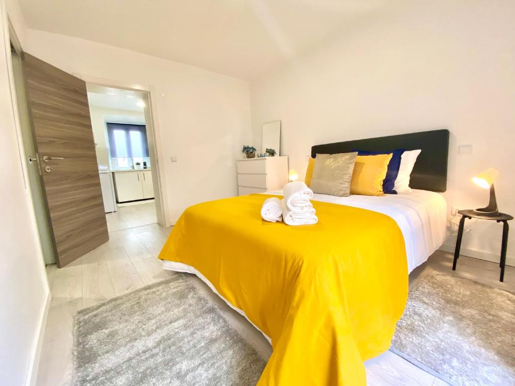 纳扎雷BrightHouse - Modern Apartments in Sítio Nazaré的一间卧室配有一张带黄色毯子的大床
