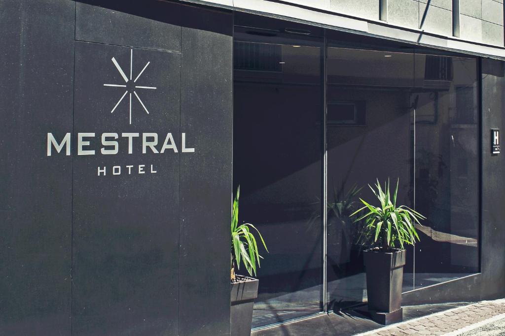 埃尔佩雷略Hotel Mestral Perelló的一座金属酒店建筑,前面有盆栽植物