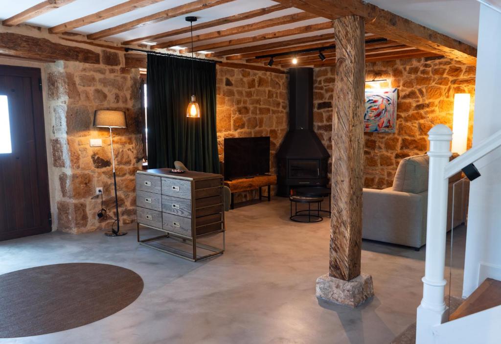El RoyoCasa Rural Pozo Roñañuela的客厅设有石墙和燃木炉。