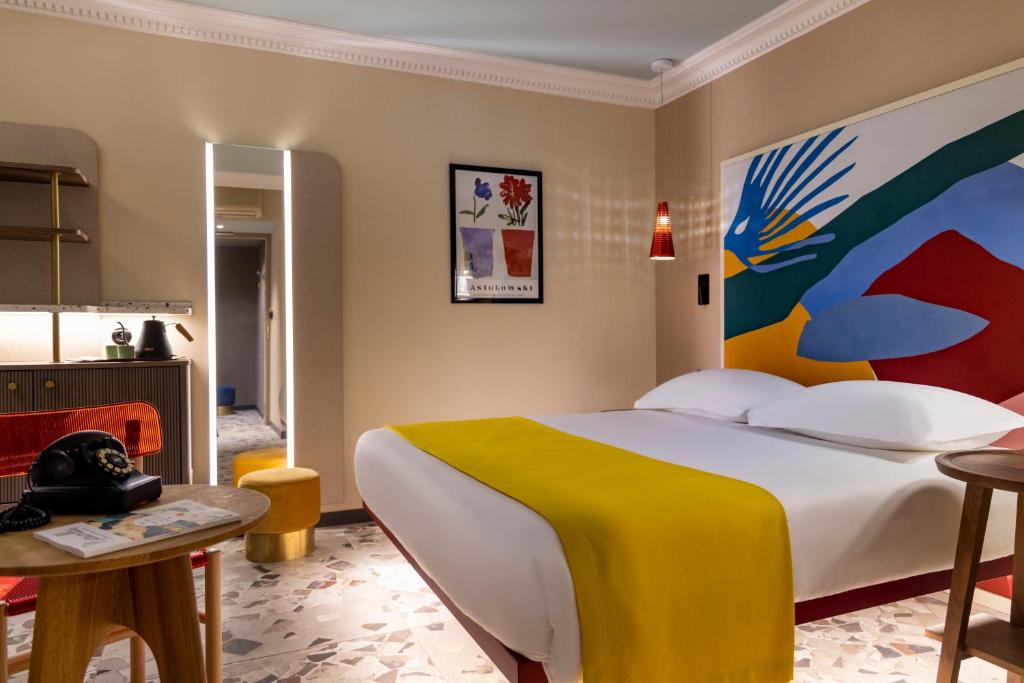 巴黎德拉帕酒店的一间卧室配有一张大床,墙上挂着一幅大画
