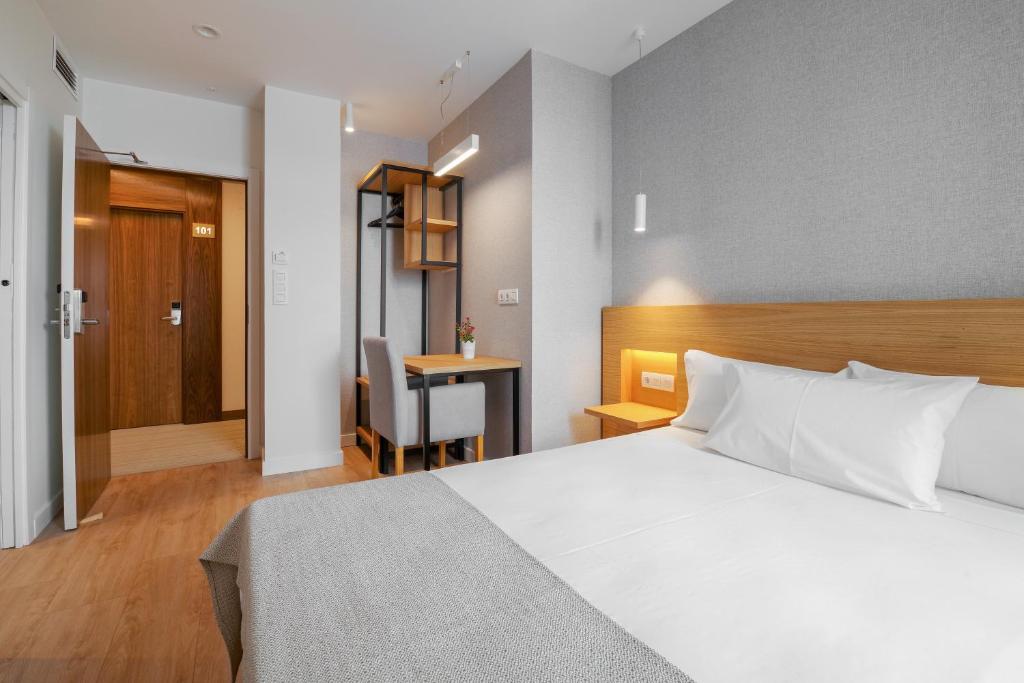 奥伦塞Hotel Condado Ourense的卧室配有白色的床和书桌