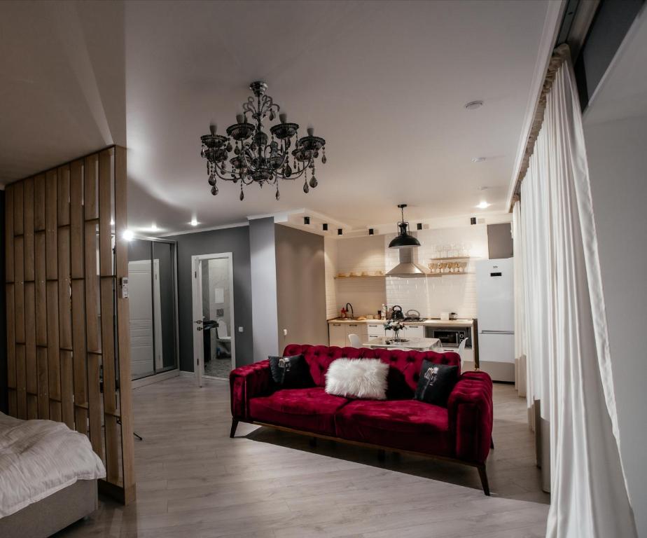 乌拉尔斯克LUX 6 МКР дизайнерская комфортная студия с панорамными дверьми и большой лоджией的一间带红色沙发的客厅和一间厨房