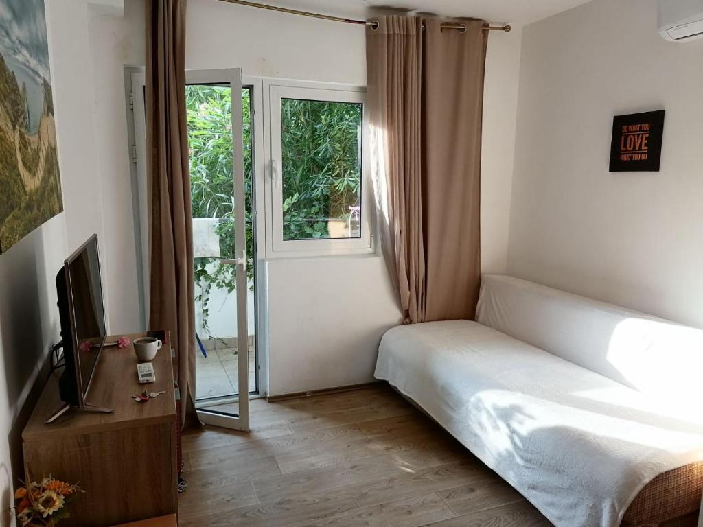 贝西奇Candy apartment central location Bečići的一间卧室配有一张床、一台电视和一个窗口