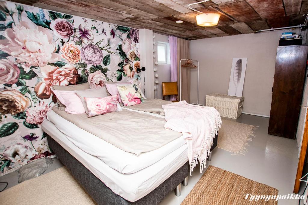 坦佩雷Tyynynpaikka的一间卧室配有一张带花卉壁纸的床