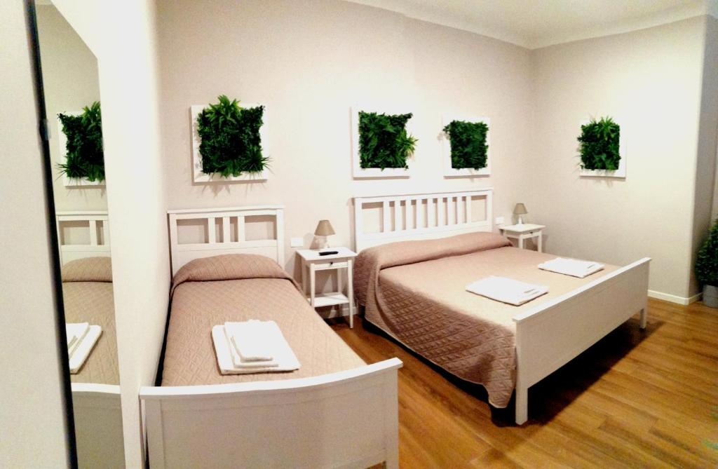 斯培西亚Bixio Suites的卧室配有两张床和两张桌子,墙上挂有植物
