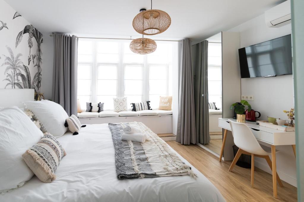 毕尔巴鄂Bilbao Art Lodge Staynnapartments的卧室配有白色的床、书桌和窗户。