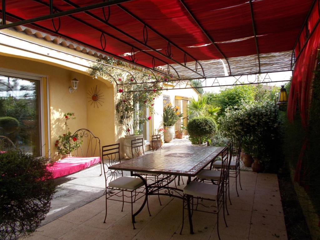 弗雷瑞斯Gîte Aux Amandiers的一个带桌椅的红色天花板庭院