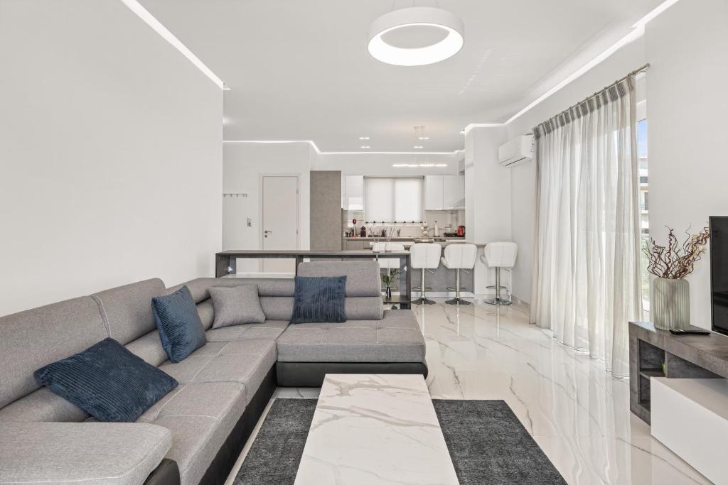雅典BillyMare central Glyfada apartment的一间带灰色沙发的客厅和一间厨房