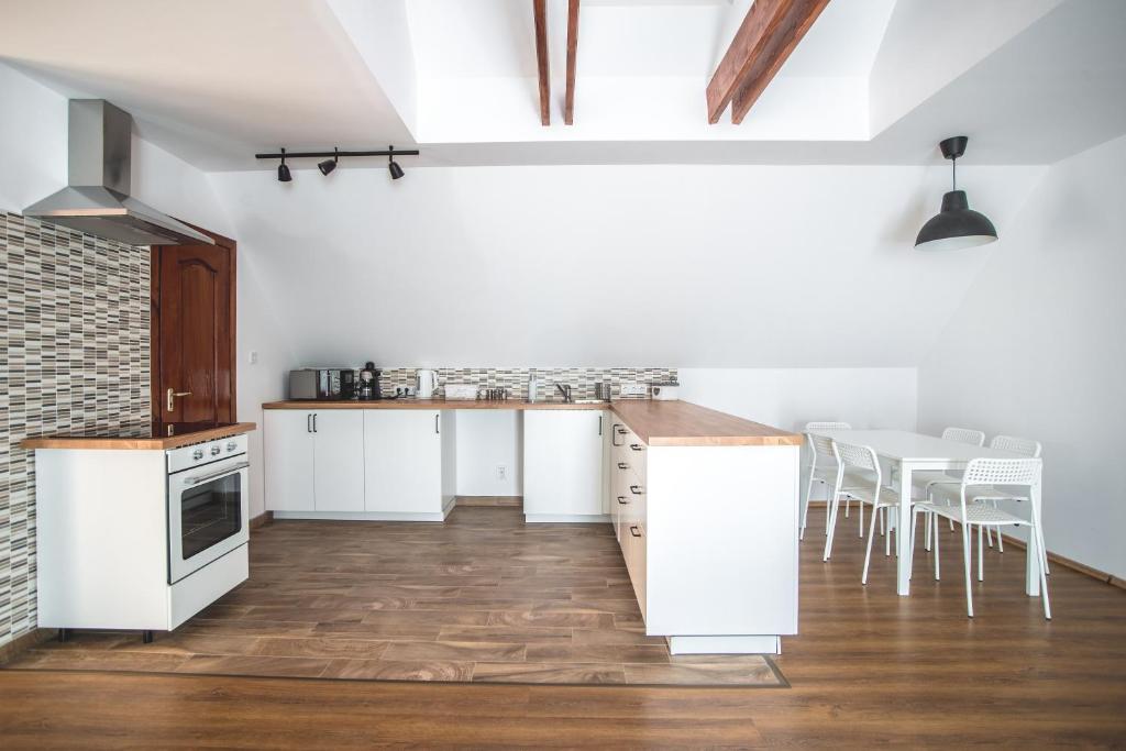 维斯普雷姆Pataky Apartmanok的厨房配有白色的柜台、白色的橱柜和椅子