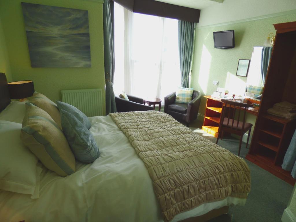 滕比Southcliff Guest House的一间卧室配有一张床、一张书桌和一个窗户。