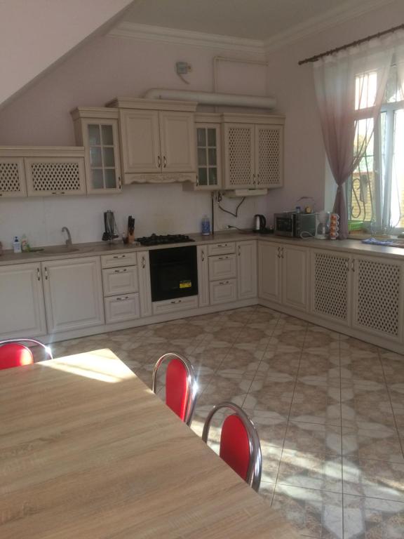 扎托卡Дом на берегу Черного Моря的厨房配有白色橱柜和红色椅子的桌子