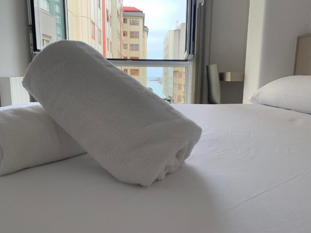 拉科鲁尼亚Oxford Suites Ciudad de la Coruña的窗户间床上的毛巾