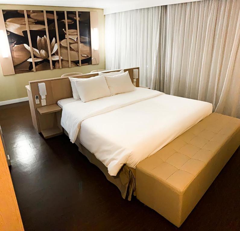 马瑙斯马瑙斯美居酒店的卧室配有一张白色大床和长凳