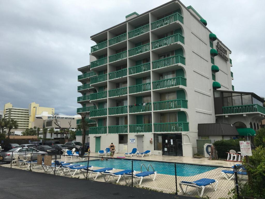 默特尔比奇Quail Inn and Suites - Myrtle Beach的大楼前设有游泳池的酒店