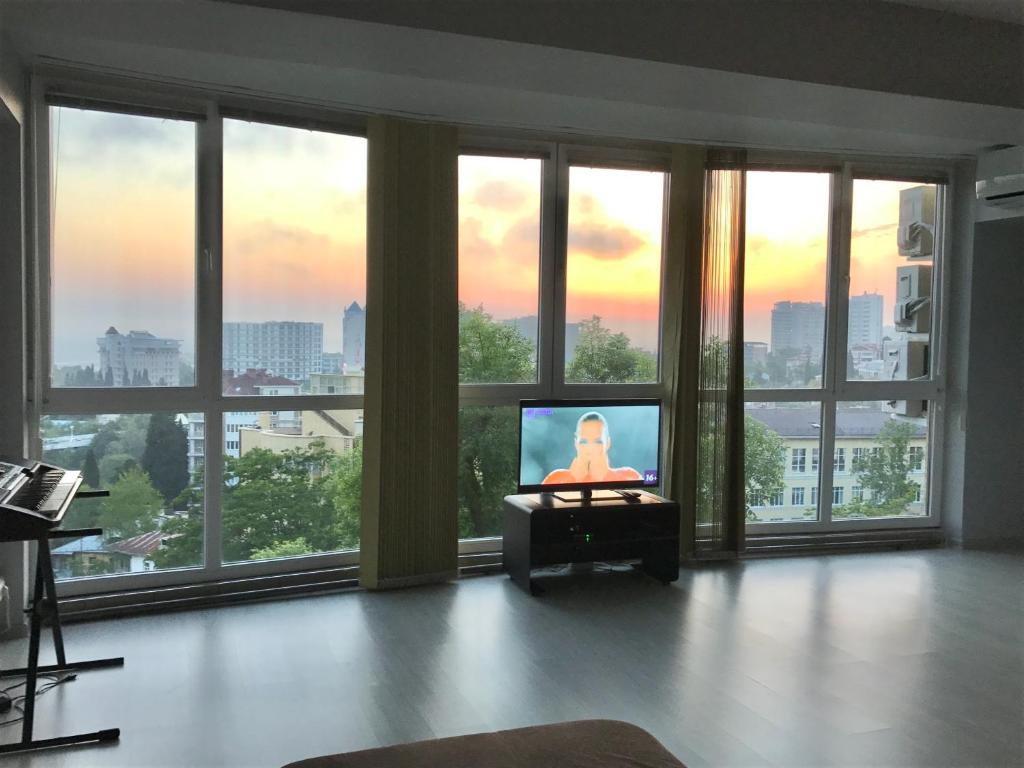 索契Apartment Lux Room的一间带电视和一束窗户的客厅