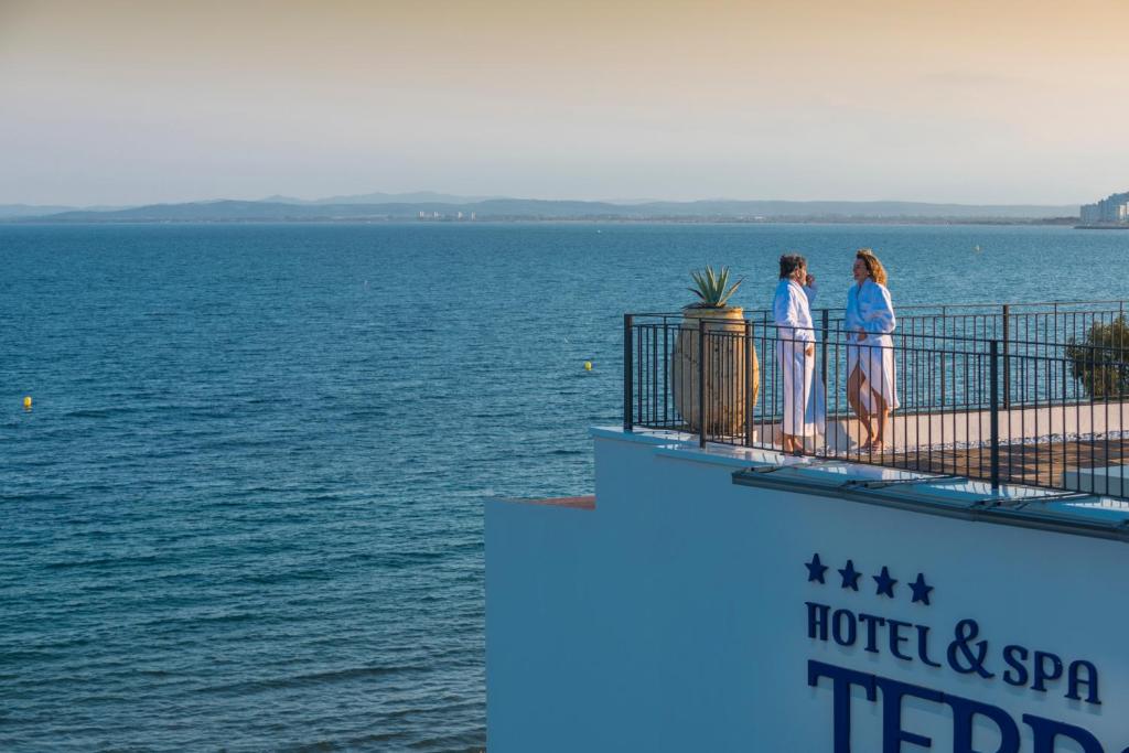 罗萨斯Hotel & Spa Terraza 4 Sup的两名妇女站在一个水景阳台上
