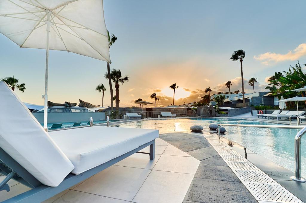 卡门港岛屿与海洋精品酒店的一个带白色沙发和遮阳伞的游泳池