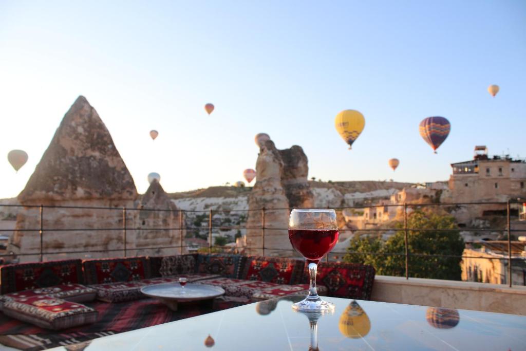 格雷梅Rose Cave Hotel的坐在桌上的一杯葡萄酒,装有热气球