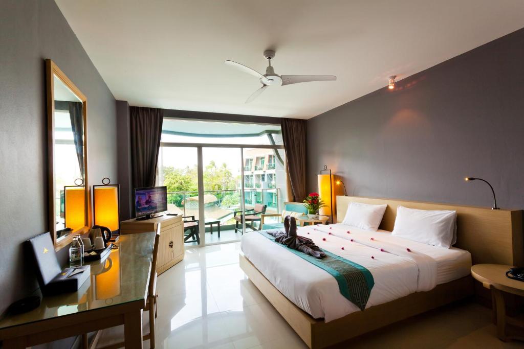 芭东海滩Ramaburin Resort Patong - SHA Extra Plus的一间卧室配有一张床、一张书桌和一台电视