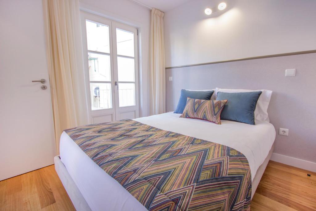 吉马良斯Santa Luzia Apartments By Guestify的卧室配有带蓝色枕头的大型白色床