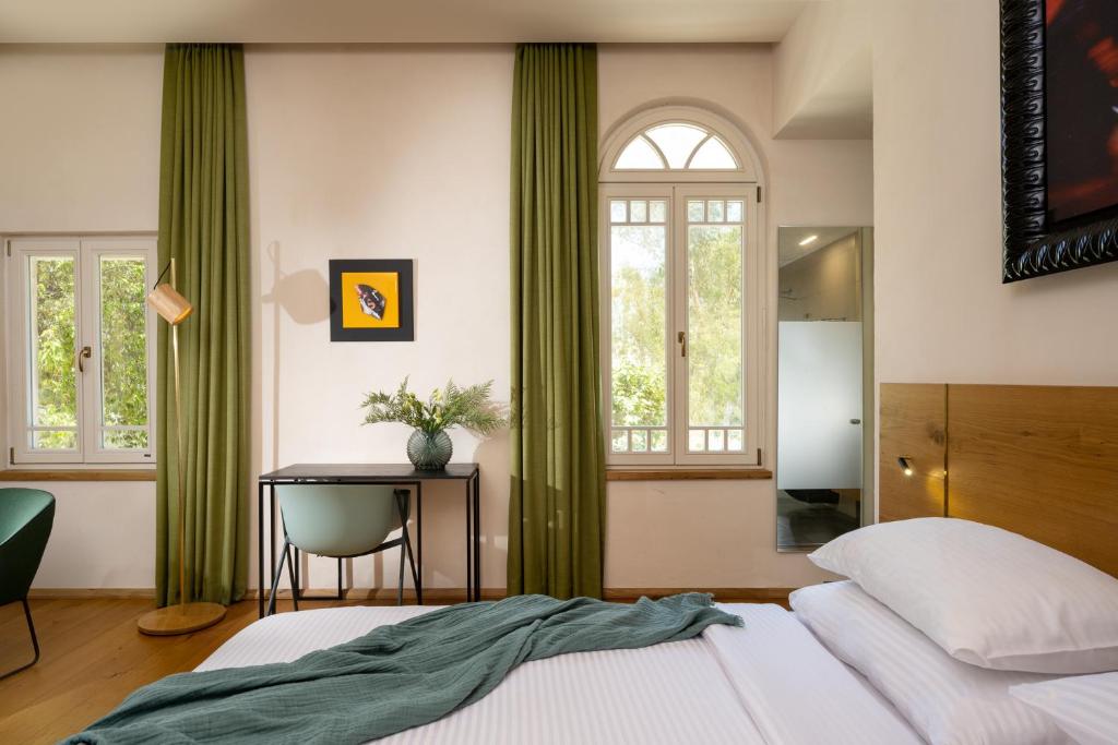 海法Schumacher Hotel Haifa的一间卧室配有绿色窗帘、一张床和一张书桌