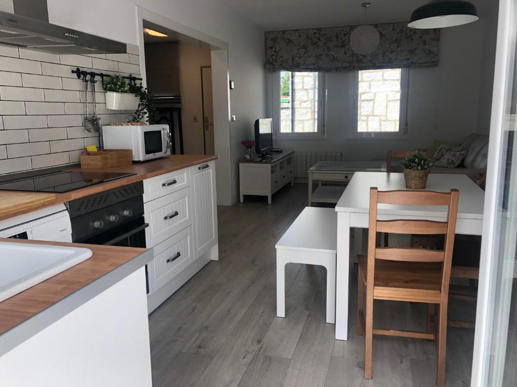 塞哥维亚Casa Navalhorno- barrio nuevo Valsain的厨房配有白色橱柜和带微波炉的桌子。