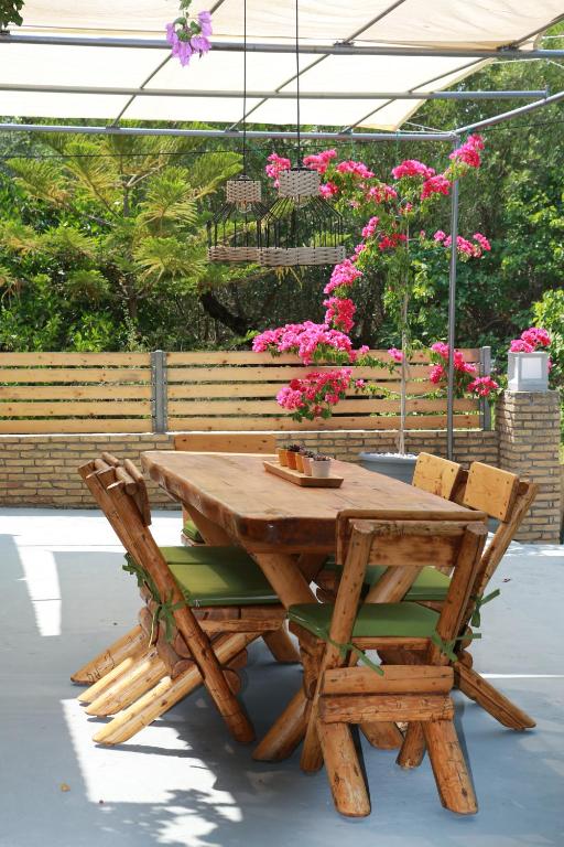 DivarataSTATHI'S COTTAGE的一张木餐桌和椅子,配以粉红色的鲜花
