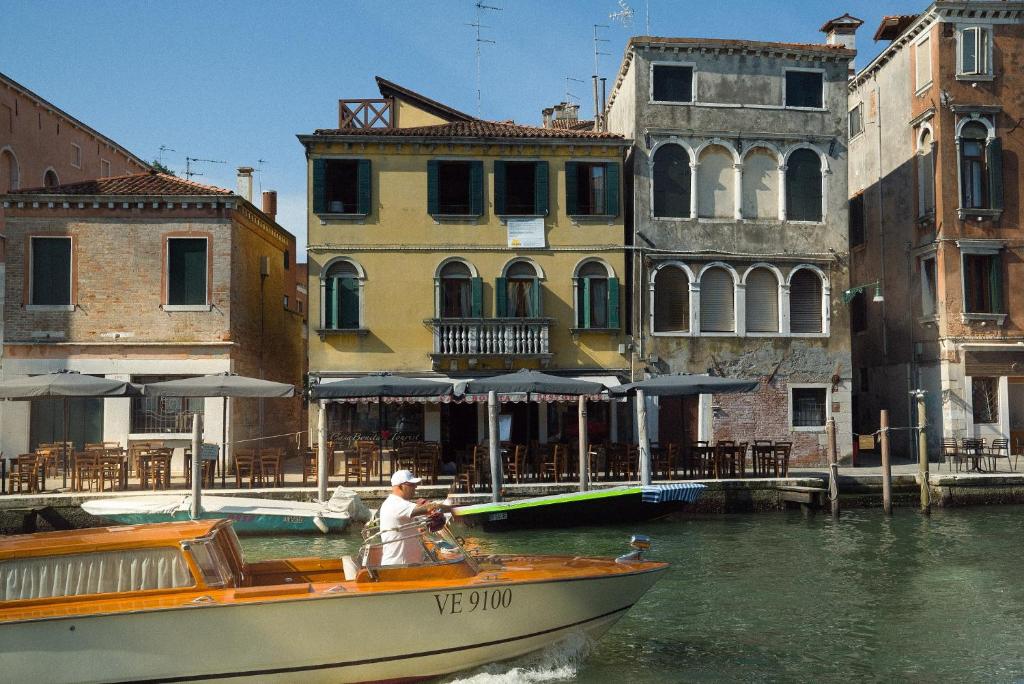 威尼斯Casa Virginia direct at the canal Cannaregio with own roof terrace的建筑物附近水中的男人