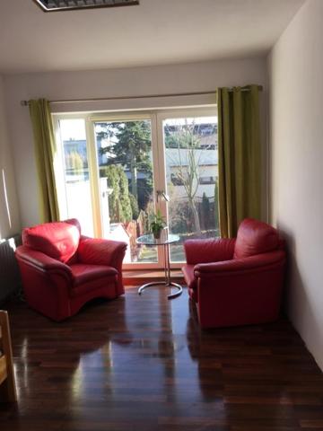 波兹南Willa Tanagra的客厅配有2把红色椅子和窗户